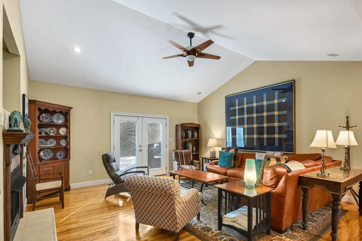 A warm and inviting living and dining area featuring a leather sofa, coffee table, fireplace, and artwork on the wall. The dining table is visible in the background, creating an open-concept space ideal for gatherings.