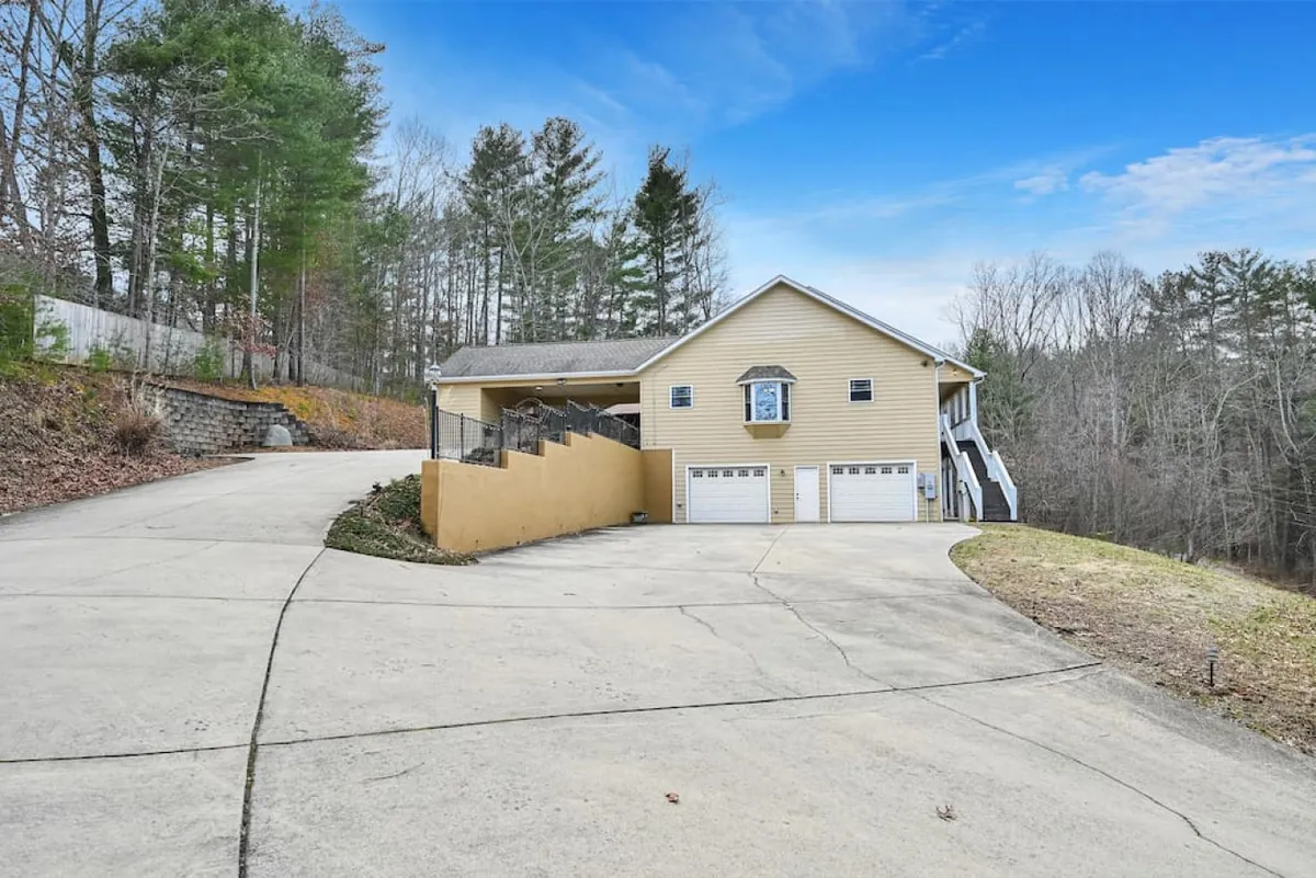 A view of the house’s exterior surrounded by greenery and trees, with a driveway leading up to it. The tranquil setting emphasizes proximity to nature and convenient access to trails, reinforcing the home as a private retreat after outdoor activities.